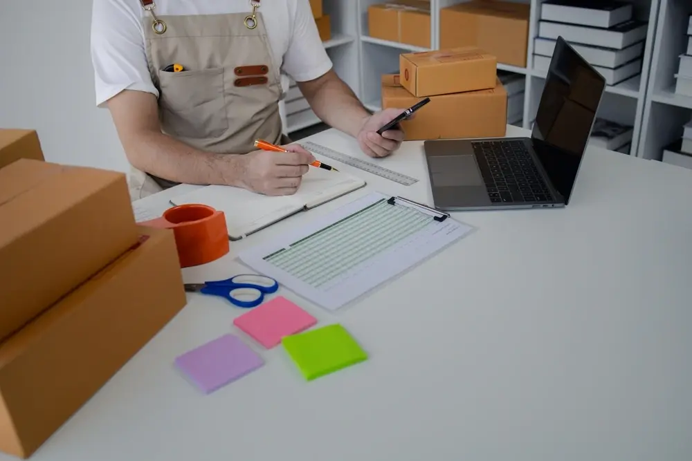 man in apron working on spreadsheet near laptop