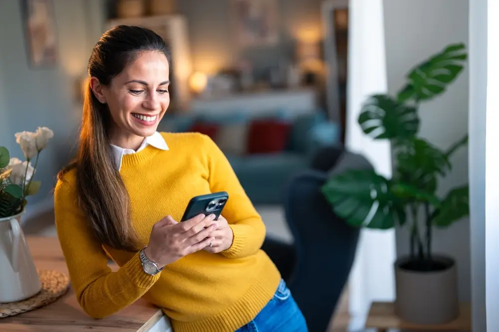 woman in yellow sweater working from iphone